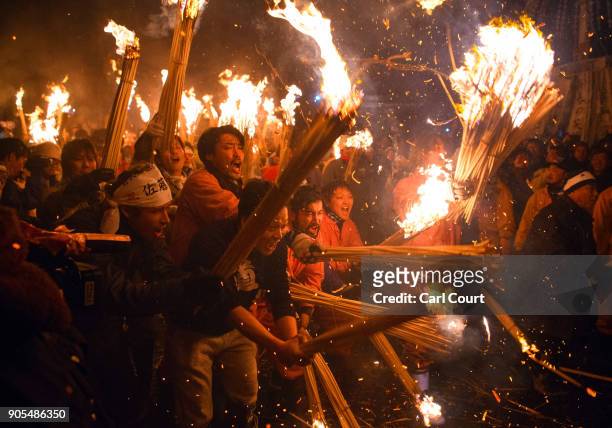 People rush forward with flaming sticks as they try to set fire to a wooden shrine that is protected by men from Nozawaonsen village during the...