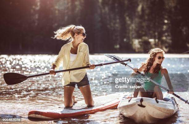 group of friends paddle boarding (sup) on lake - remo em pé imagens e fotografias de stock