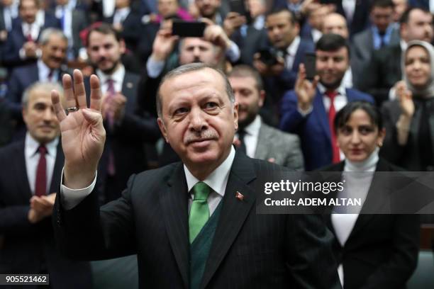 Turkish President Recep Tayyip Erdogan makes a four-finger sign as he greets people during the Justice and Development Party group meeting at the...