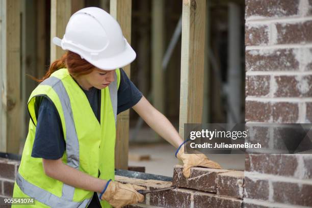 woman bricklayer preparing laying bricks on wall - pedreiro imagens e fotografias de stock