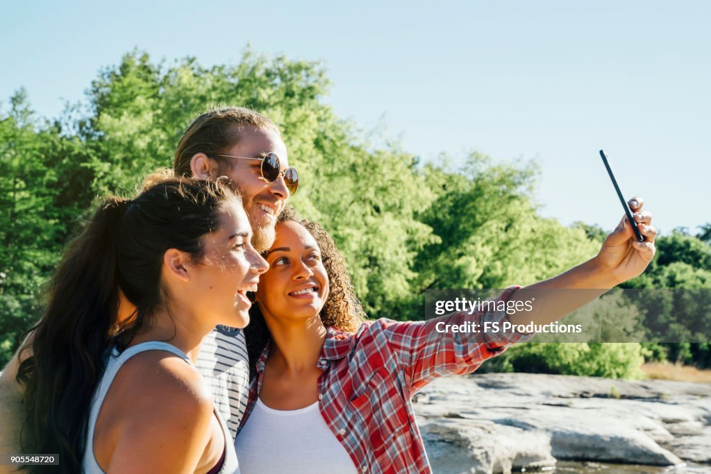 Friends posing for cell phone selfie outdoors