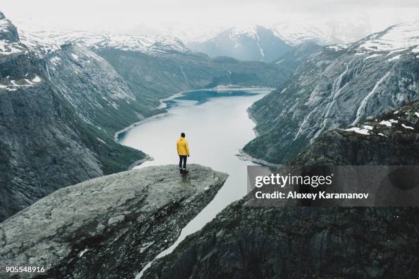 caucasian man on cliff admiring scenic view of mountain river - norway winter stock pictures, royalty-free photos & images