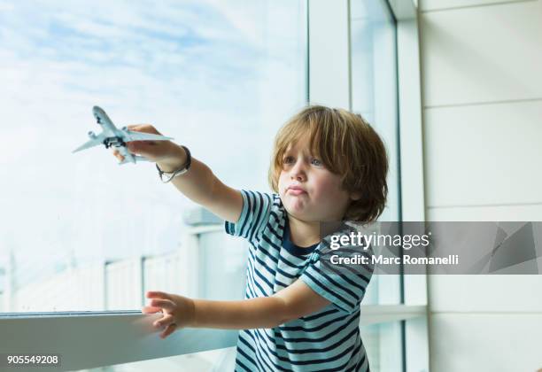 caucasian boy playing with toy airplane near window - model aeroplane stock pictures, royalty-free photos & images