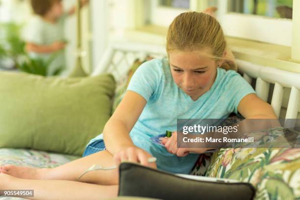 caucasian girl sitting on sofa watching digital tablet - saint simons island stock-fotos und bilder