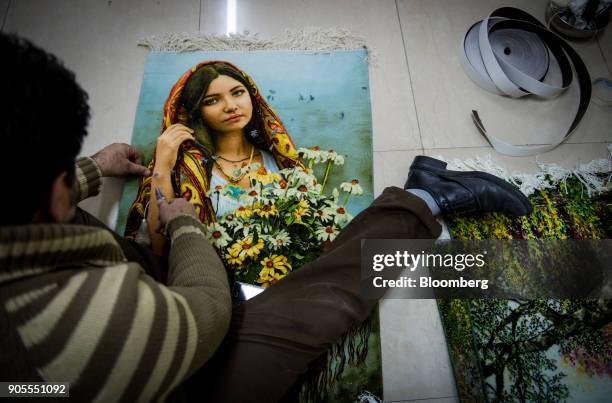 Man darns a small carpet with a scene of a young woman holding flowers in the rug bazaar in Tehran, Iran, on Monday, Jan. 15, 2018. The U.S....