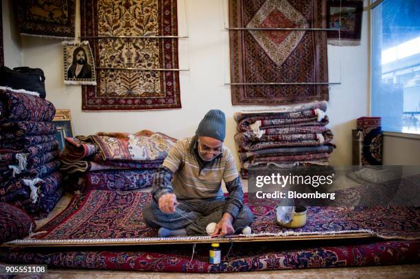 Man darns a Persian carpet inside a store at the rug bazaar in Tehran, Iran, on Monday, Jan. 15, 2018. The U.S. President plans on sticking with an...
