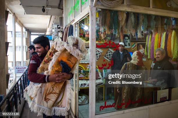 Salesman carries an armful of small rugs past a woollen thread shop at the rug bazaar in Tehran, Iran, on Monday, Jan. 15, 2018. The U.S....