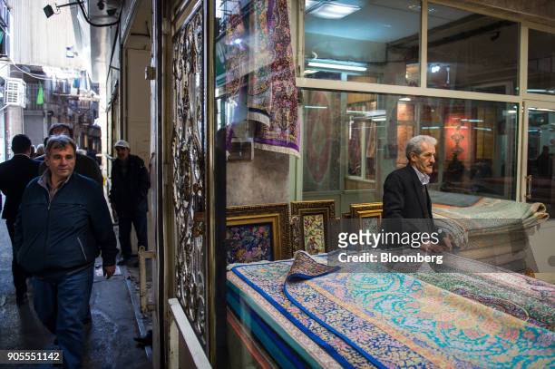Visitors pass the window of a carpet seller in the rug bazaar in Tehran, Iran, on Monday, Jan. 15, 2018. The U.S. President plans on sticking with an...
