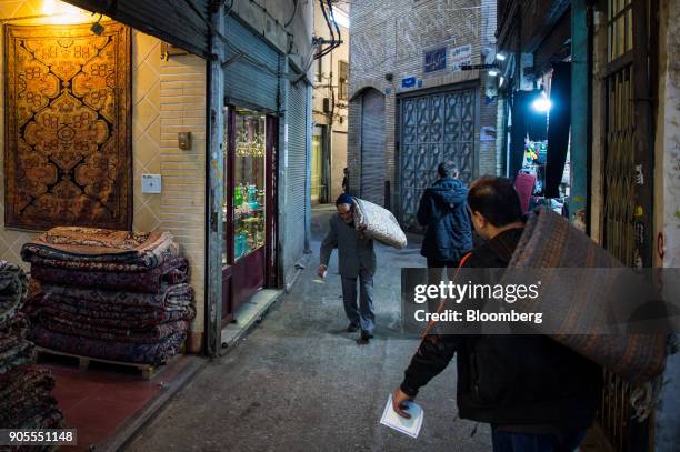 Men carry folded carpets on their shoulders as they walk through the rug bazaar in Tehran, Iran, on Monday, Jan. 15, 2018. The U.S. President plans...