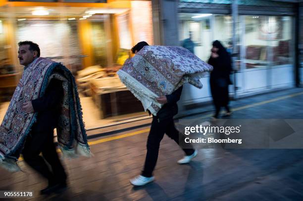 Two man carry Persian carpets on their shoulders through the rug bazaar in Tehran, Iran, on Monday, Jan. 15, 2018. The U.S. President plans on...