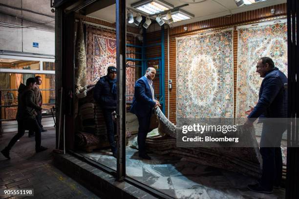 Two men check the quality of Persian carpets in a store at the rug bazaar in Tehran, Iran, on Monday, Jan. 15, 2018. The U.S. President plans on...