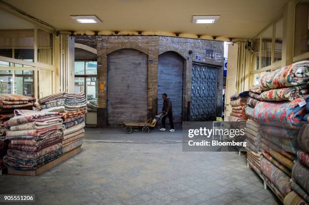 Man pushes a trolley past a store of folded Persian carpets in the rug bazaar in Tehran, Iran, on Monday, Jan. 15, 2018. The U.S. President plans on...