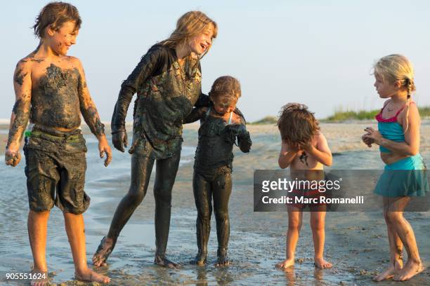 caucasian brothers and sisters covered in mud playing on beach - preteen girl no shirt stock pictures, royalty-free photos & images