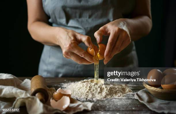 caucasian woman cracking egg over flour - recipe imagens e fotografias de stock