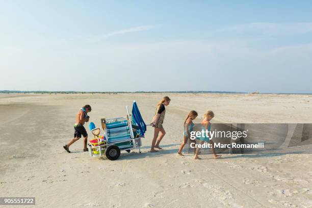 caucasian boy and girls pulling cart on beach - saint simons island stock-fotos und bilder