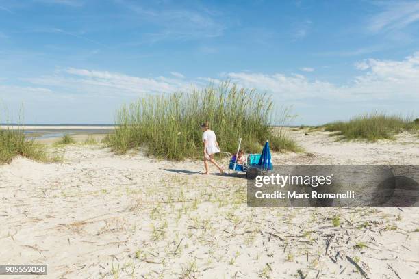 caucasian mother pulling son in cart on the beach - saint simons island stock-fotos und bilder