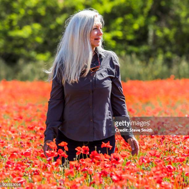 caucasian woman looking away in field of flowers - stehmohn stock-fotos und bilder