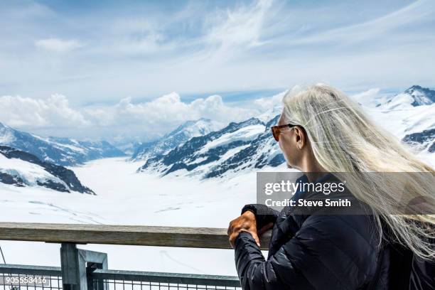 caucasian woman leaning on railing admiring scenic view of mountains - grindelwald stock pictures, royalty-free photos & images