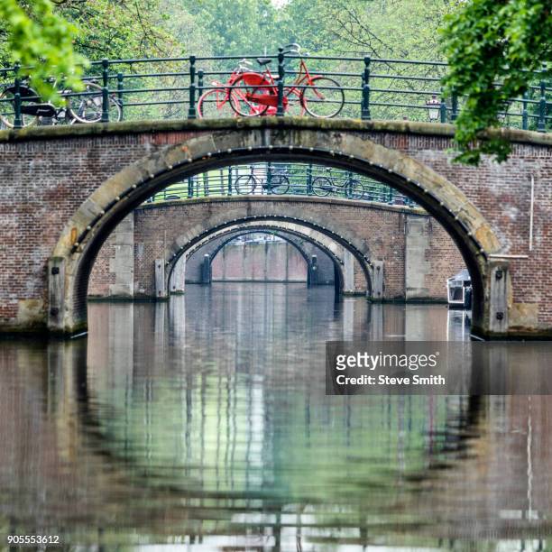 bicycles on bridges over urban canal - amsterdam canal stockfoto's en -beelden