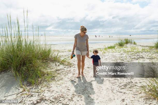 caucasian mother and son walking on beach - saint simons island stock-fotos und bilder