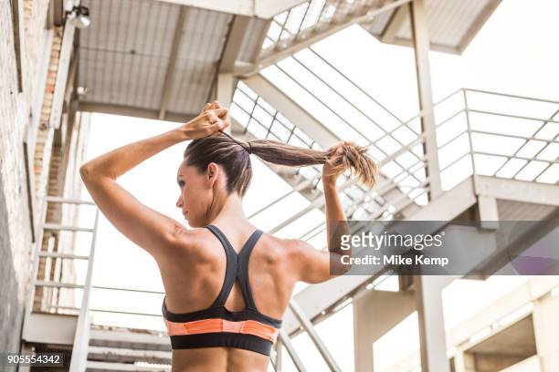 caucasian woman tying hair in ponytail - hair back ストックフォトと画像