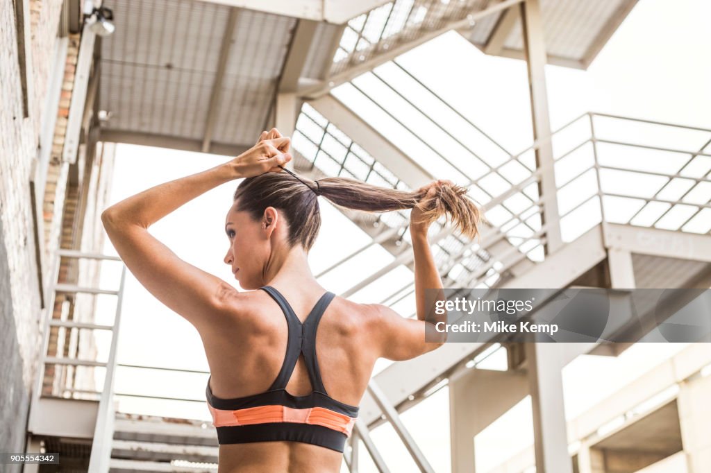 Caucasian woman tying hair in ponytail