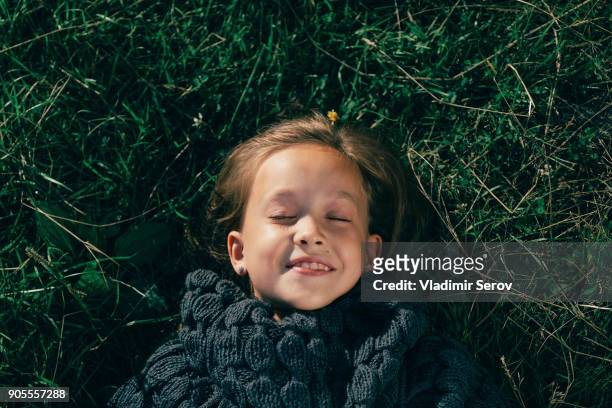 caucasian girl wearing sweater laying in grass - kid lying down stock pictures, royalty-free photos & images