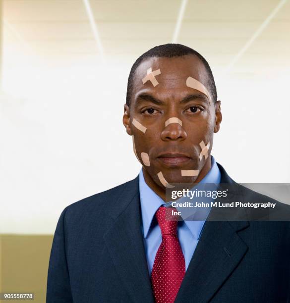 close up of mixed race businessman with bandages on face - head wound - fotografias e filmes do acervo