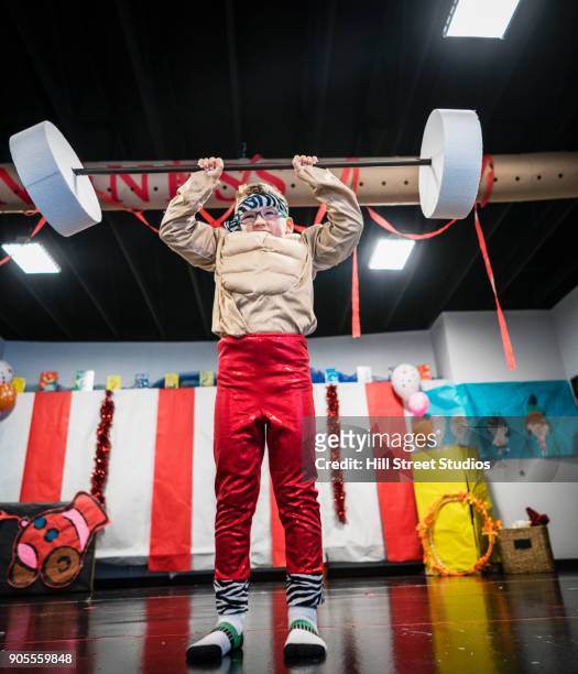 caucasian boy in strongman costume lifting toy barbell - young kid and barbell stock-fotos und bilder