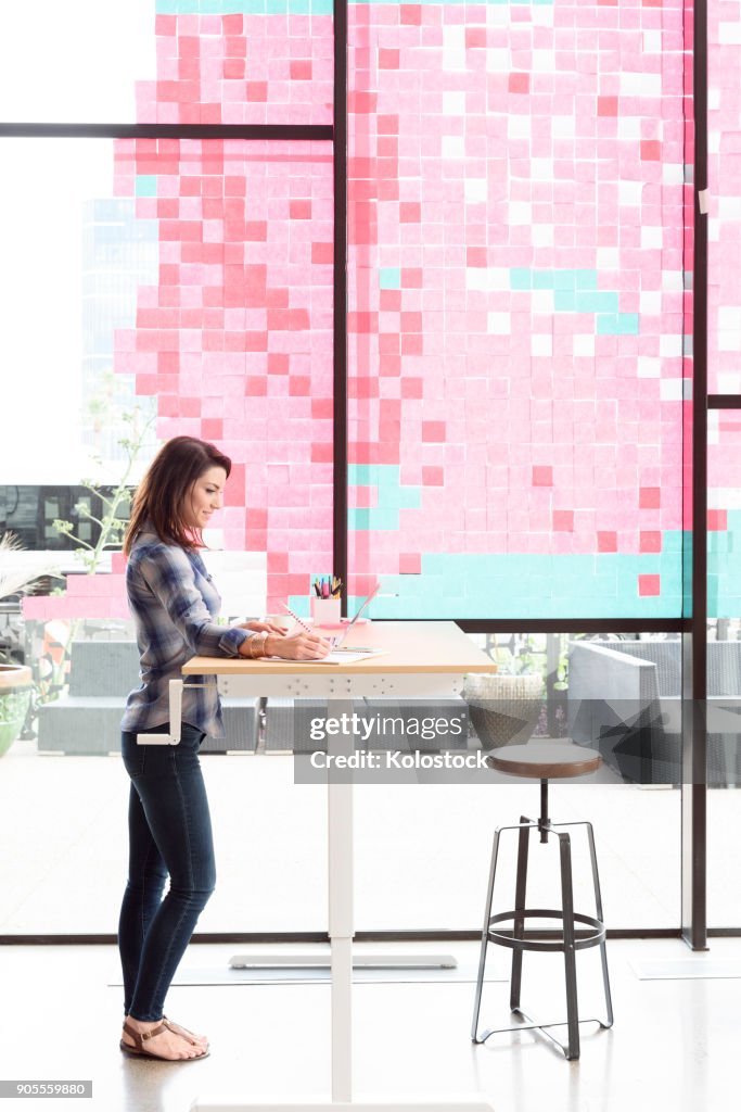 Caucasian woman using laptop at standing workstation