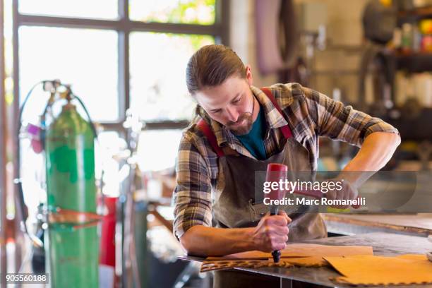 caucasian man hammering leather - leather craft stock pictures, royalty-free photos & images