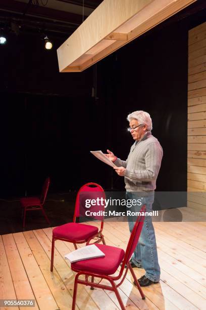 hispanic man reading script on theater stage - monoloog fotografías e imágenes de stock