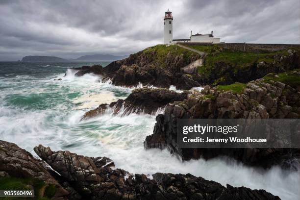 ocean waves crashing on rocks near lighthouse - headland stock-fotos und bilder