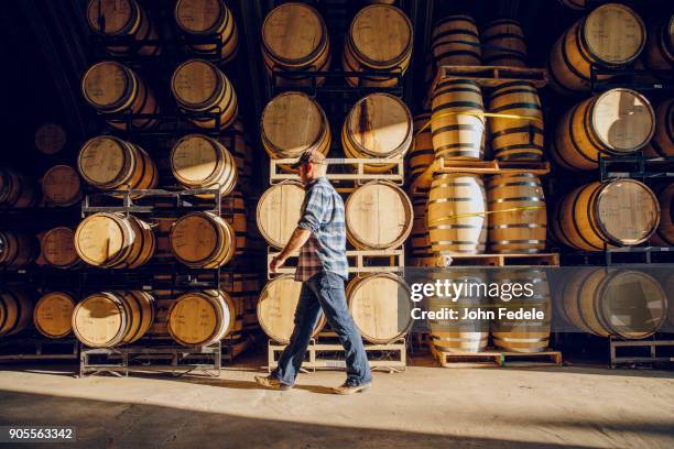 caucasian man walking near barrels in distillery - barrels ストックフォトと画像