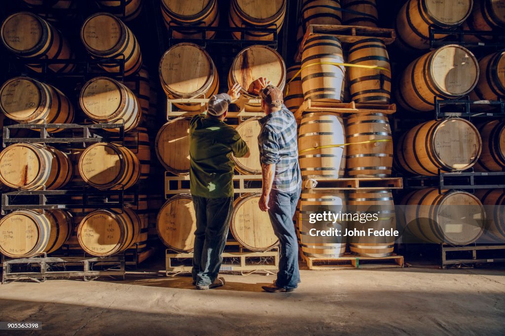 Caucasian men examining barrel in distillery