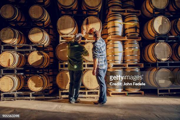 caucasian men examining barrel in distillery - winemaking - fotografias e filmes do acervo