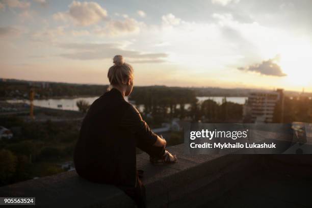 caucasian woman on roof admiring scenic view of sunset - nur frauen balkon stock-fotos und bilder