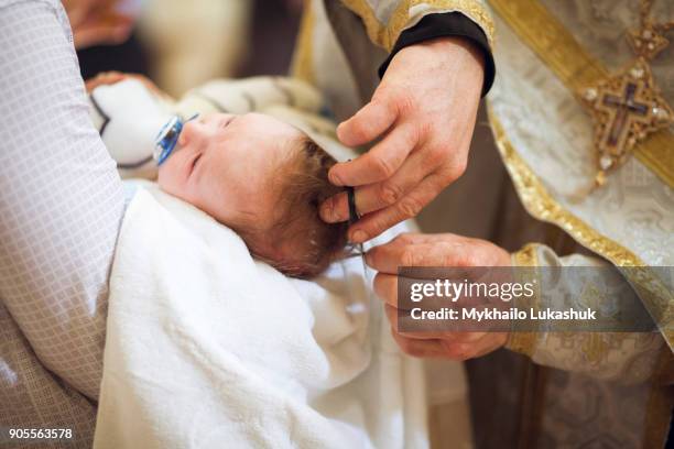 priest clipping hair of baby girl - dopen stockfoto's en -beelden