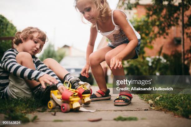 caucasian girl helping boy with rollerskates - brest belarus stock pictures, royalty-free photos & images