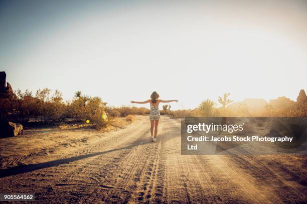 hispanic woman walking on dirt road - arms outstretched silhouette stock pictures, royalty-free photos & images