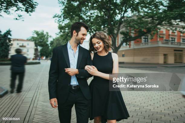 smiling caucasian couple walking arm in arm - braços dados imagens e fotografias de stock