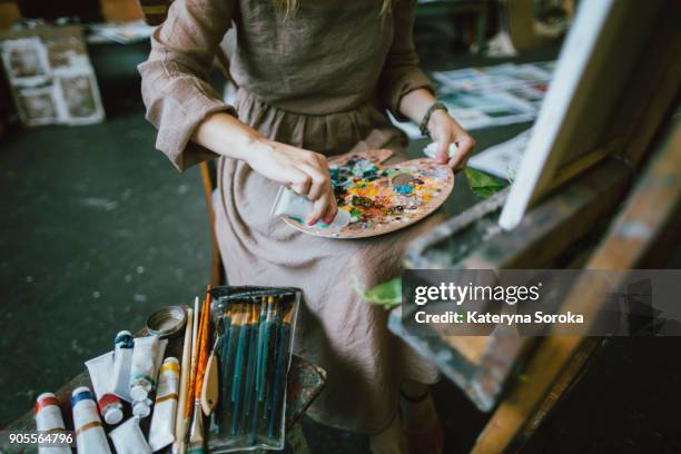 caucasian woman squeezing paint onto palette - schilder kunstenaar stockfoto's en -beelden