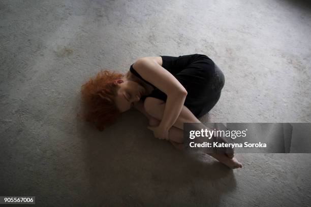 caucasian woman laying on concrete in fetal position - position du foetus photos et images de collection