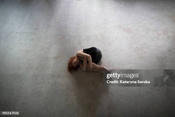 caucasian woman laying on concrete in fetal position - position du foetus photos et images de collection