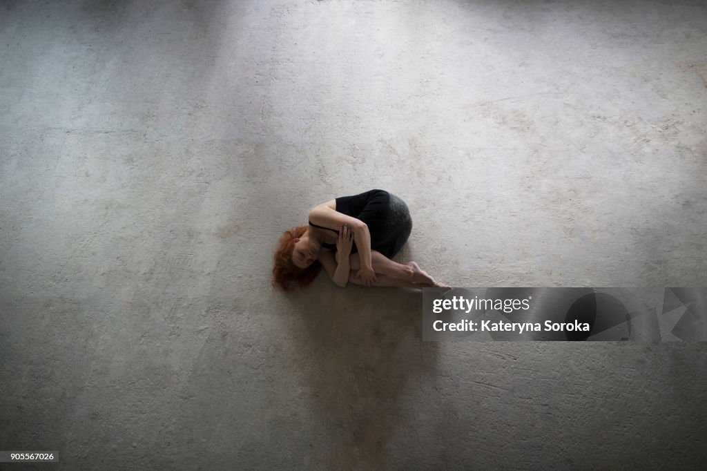 Caucasian woman laying on concrete in fetal position