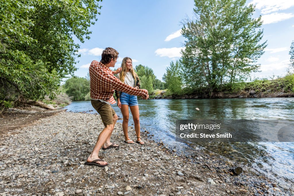 Caucasian couple skipping stones in river