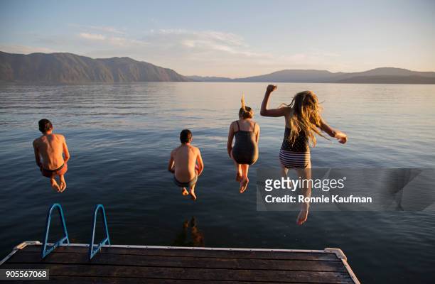 boys and girls jumping off a dock into lake - boy swimming stock-fotos und bilder