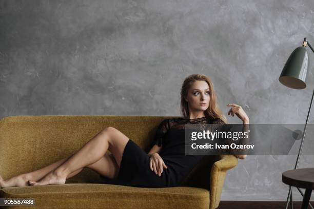 glamorous caucasian woman sitting on sofa - kanten jurk stockfoto's en -beelden