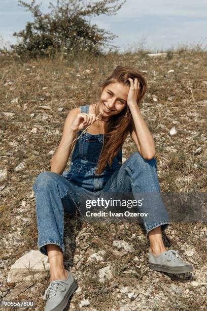 caucasian woman wearing overalls sitting in rocky field - simferopol stock pictures, royalty-free photos & images