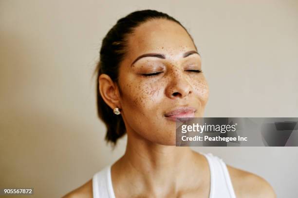 close up of mixed race woman with eyes closed - sommersprossen stock-fotos und bilder